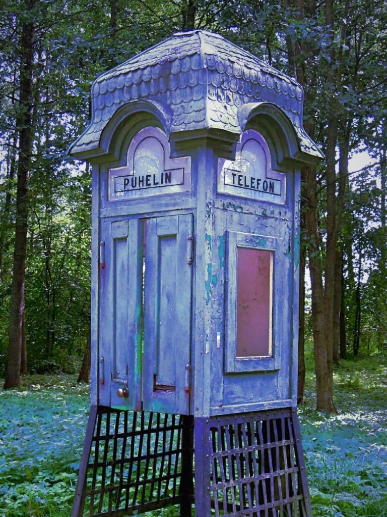 Rote Telefonzelle mit weißem Schriftzug "TELEPHONE" auf der Vorderseite.