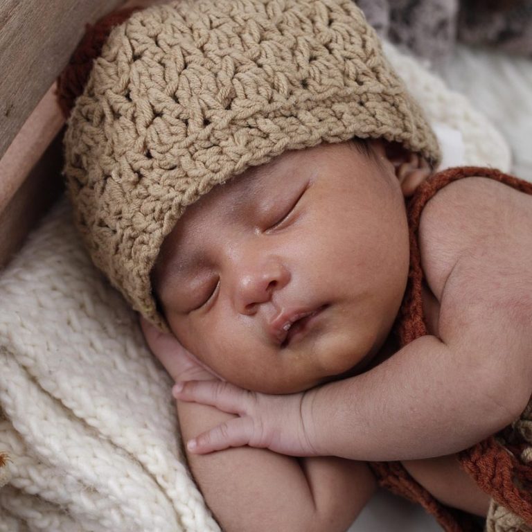 Baby schläft friedlich mit einer gestrickten Mütze.